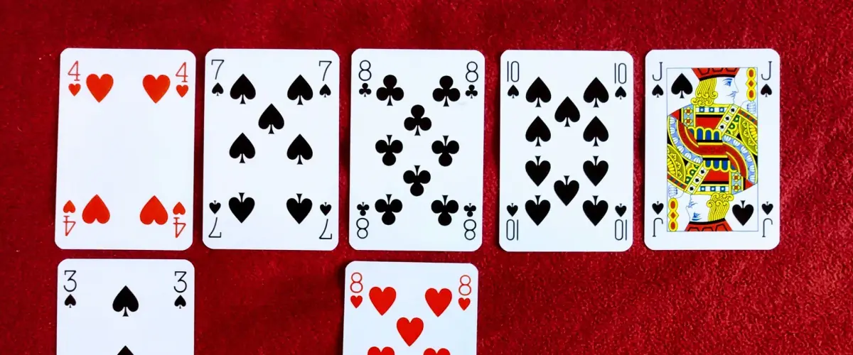 Playing cards laid out in rows on red felt